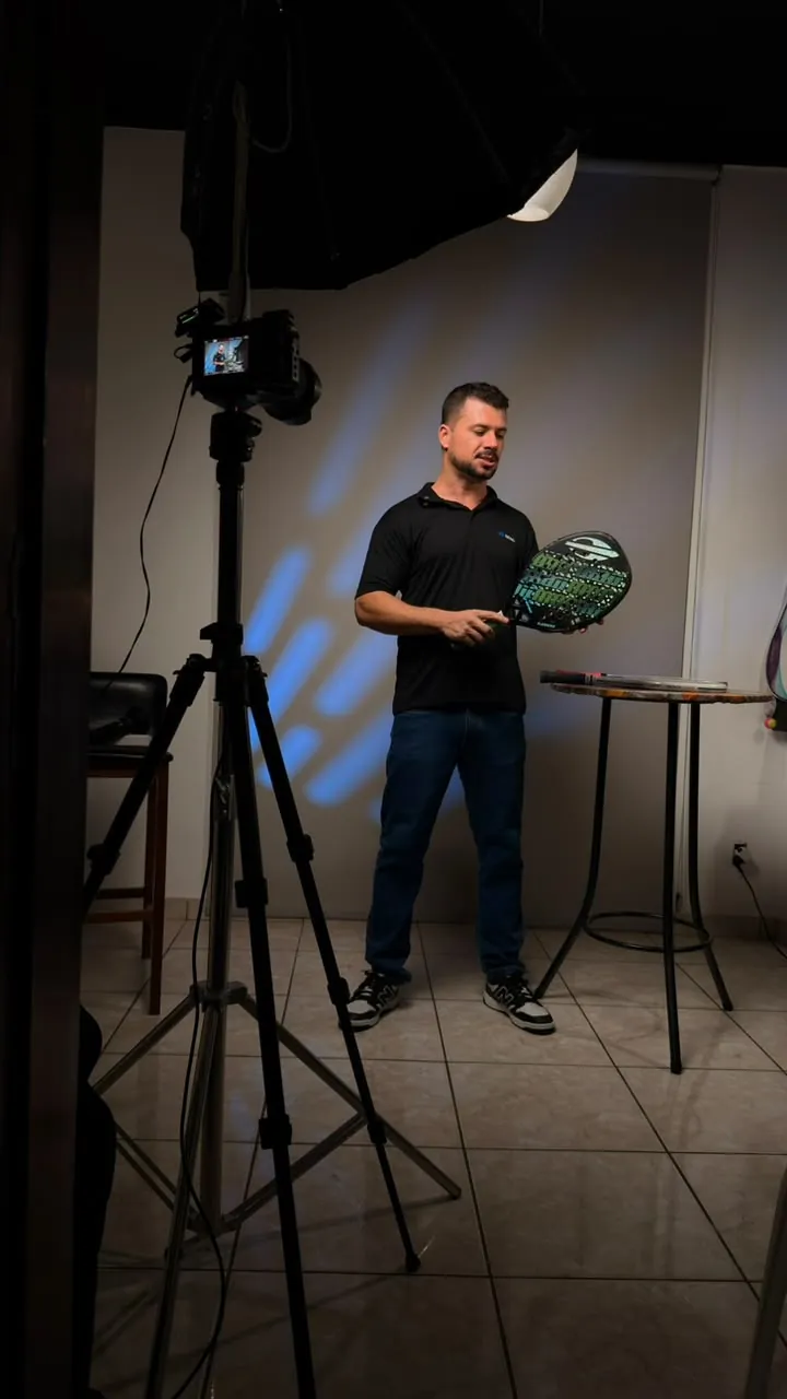Ronan grava uma aula do curso mostrando uma raquete de beach tennis para a câmera